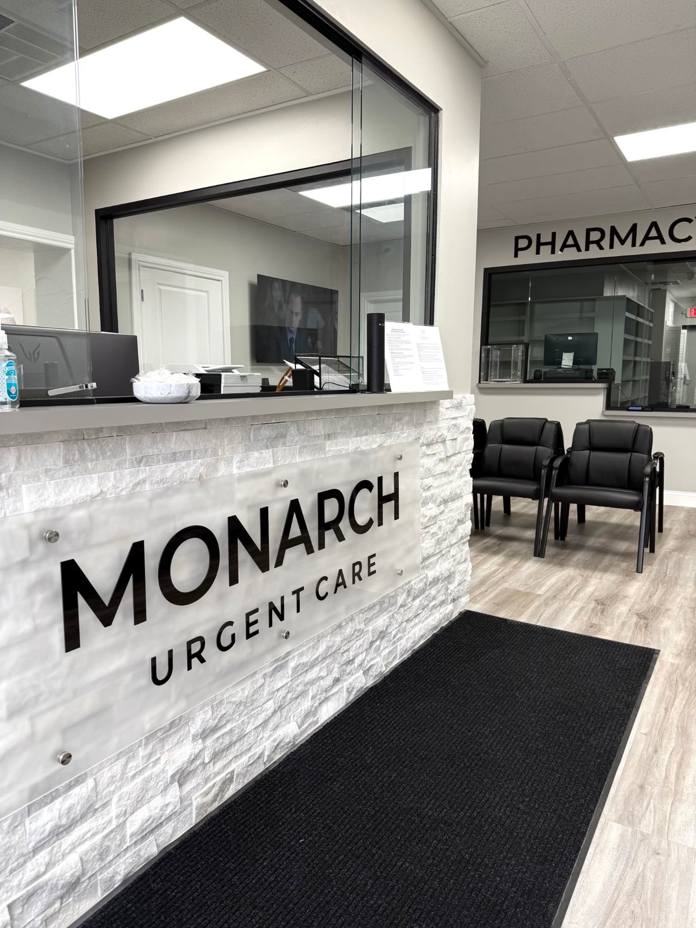 The Monarch Urgent Care reception desk, with the pharmacy window and waiting area behind it
